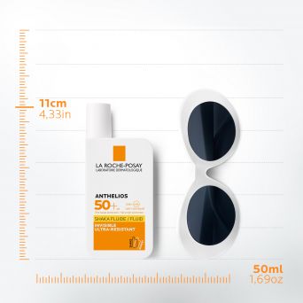 La Roche-Posay Anthelios Shaka Fluid SPF50+ 50ml sunscreen bottle placed next to sunglasses showing compact 11 cm travel-friendly size