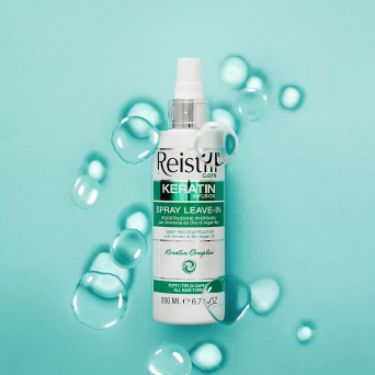 Reistill Keratin Infusion Spray Leave-In 200ml on aqua background with water droplets, deep reconstructing keratin and argan oil leave-in for all hair types